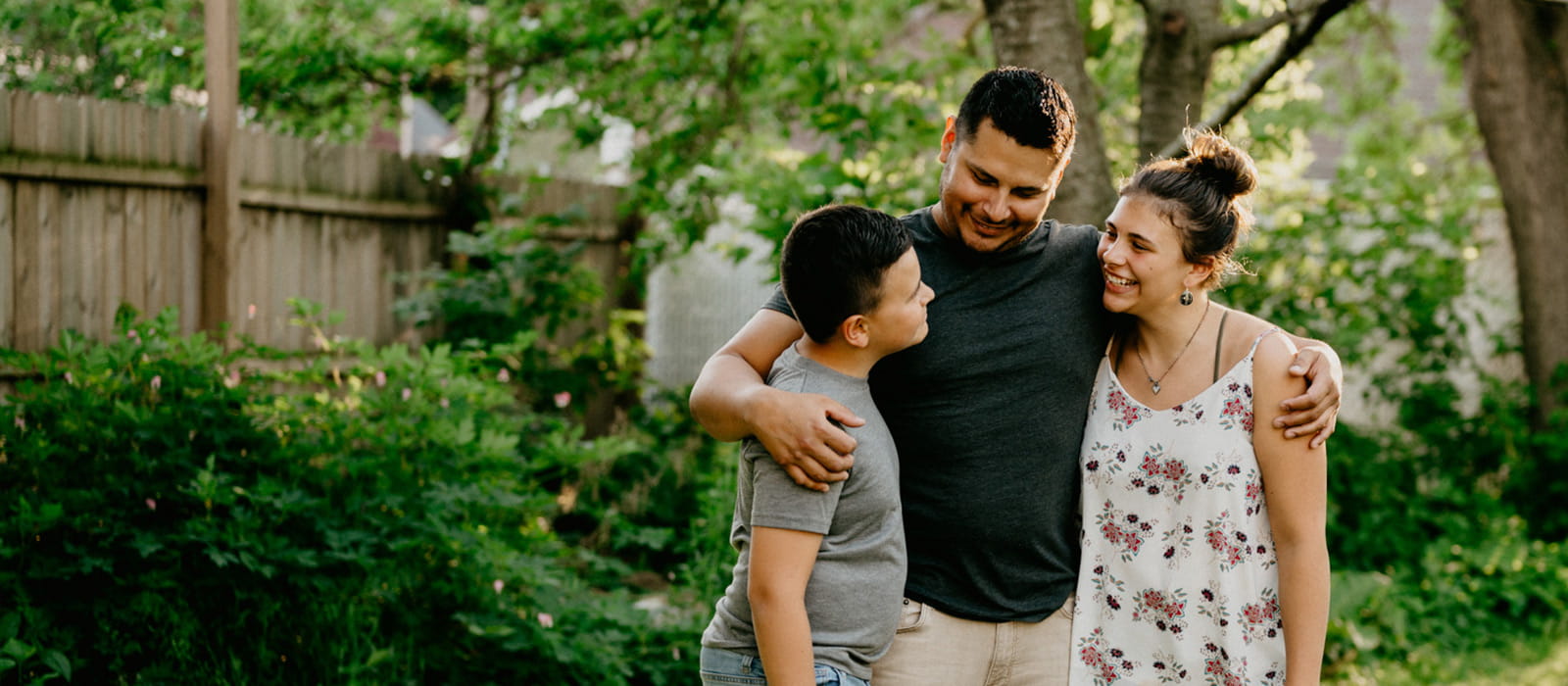 Family standing in yard embracing and  smiling at each other.